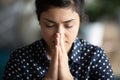 Closeup religious indian female closed eyes praying with folded palms