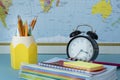 Close up image of school supplies and black round clock on map background. Royalty Free Stock Photo