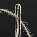 A close-up image of a shiny metallic sewing needle with a large eye, through which a Royalty Free Stock Photo