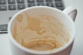 Empty espresso cup with visible coffee residue in foreground and laptop keyboard in soft background creating a modern workspace Royalty Free Stock Photo