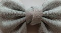 A close-up image of a silver textured bow tie. The fabric is woven with a tight, intricate pattern, Royalty Free Stock Photo