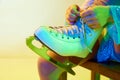 Close-up image of skates. Girl, child tying laces on skates before dancing against yellow background in neon light Royalty Free Stock Photo