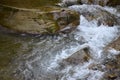 Close-up image of a small wild waterfall in the form of short streams of water between mountain stones Royalty Free Stock Photo