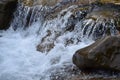 Close-up image of a small wild waterfall in the form of short streams of water between mountain stones