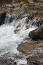 Close-up image of a small wild waterfall in the form of short streams of water between mountain stones Royalty Free Stock Photo