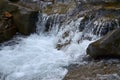 Close-up image of a small wild waterfall in the form of short streams of water between mountain stones Royalty Free Stock Photo