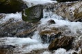 Close-up image of a small wild waterfall in the form of short streams of water between mountain stones Royalty Free Stock Photo