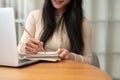 Close-up image of a smart Asian female college student writing in her notebook, doing homework Royalty Free Stock Photo