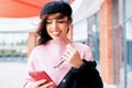 Close-up image of smiling happy woman standing outdoors texting message on mobile phone. Young female wears pink sweater, black Royalty Free Stock Photo