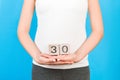 Close up image of thirty weeks of pregnancy cubes in pregnant woman`s hands at blue background. Happy pregnancy. Copy space