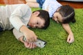 Close up image of two asian cute and smart little boy and girl lying on green floor while using or playing game from cell phone Royalty Free Stock Photo