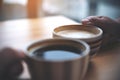 Two people clink coffee cups on wooden table in cafe