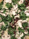 Close up image of a Valtellina pizza topped with bresaola, rocket, fresh mushrooms and shavings of grana cheese