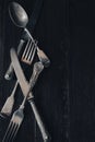 A close up image of vintage metal cutlery lying on on a rustic wooden surface