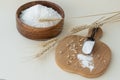 Close up image of wheat flour in wooden bowl and in spoon on board, near ears of wheat and some grains on light background. Royalty Free Stock Photo