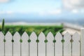 Close up image of white picket fence with beautiful beach scenery out of focus in background providing copy space Royalty Free Stock Photo