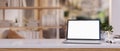 Close-up image of a white-screen laptop computer and accessories on a wooden desk in a modern room Royalty Free Stock Photo