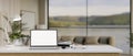 Close-up image of a white-screen laptop mockup on a white tabletop in a modern spacious living room Royalty Free Stock Photo