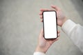A white-screen smartphone mockup in a woman's hand over a blurred street in the background. Royalty Free Stock Photo
