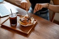 Close-up image of a woman eating a yummy croissant roll, and iced coffee in a cafe