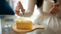 Close-up image of a woman enjoys eating a yummy cake while relaxing in a coffee shop