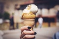 Close up image of woman hand holding fresh waffle cone with vanilla and raspberry ice cream on the wooden background. Royalty Free Stock Photo