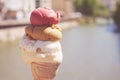 Close up image of woman hand holding fresh waffle cone with vanilla and raspberry ice cream on the wooden background. Royalty Free Stock Photo