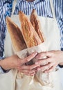 Close-up image of woman holding package of fresh baguettes. Royalty Free Stock Photo