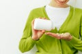 Close-up image of woman`s hand pours the pills out of the bottle. Healthy female wearing green cardigan and white t shirt pouring Royalty Free Stock Photo