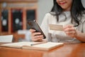 Close-up image of a woman using her smartphone and her credit card in a coffee shop Royalty Free Stock Photo