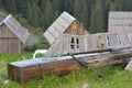 Close up image of wood log made water basin with running pipe water and view of forest behind