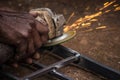 Close up of man sharpening iron with an equipment