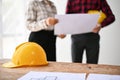 Close-up image of a yellow safety helmet hat and blueprint are on a table Royalty Free Stock Photo