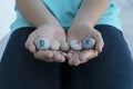 close up image of young female hands hold gray round stones with colorful inscription relax on them.