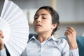 Indian woman closed eyes use fan cooling herself feels overheated