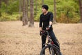 Close up image of young man standing near his bike on forest road, stops to have rest, riding bike on weekends, spending free time Royalty Free Stock Photo