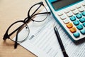 Close up income tax return planning ,1040 tax form, with calculator, pen and eye glasses place on the wooden table