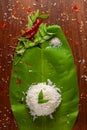 Close-up of Indian cooked rice over the banana fresh green leaf. Garnished with curry-patta leaves and red chilli paper