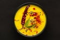 Close-up of Indian traditional kadhi or kadi pakora yogurt and gram flour and turmeric served hot in a black bowl.