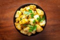 Close-up of Indian vegetarian classic dish Jeera Aloo - Potatoes Flavored with Cumin garnished with green coriander fresh leaves.