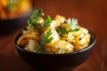 Close-up of Indian vegetarian classic dish Jeera Aloo - Potatoes Flavored with Cumin garnished with green coriander fresh leaves.