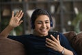 Close up Indian woman in headphones waving hand, using smartphone Royalty Free Stock Photo