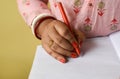 Close up of an Indian woman's hands writing in notepad with pen placed on hand Royalty Free Stock Photo