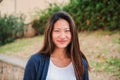 Close up individual portrait of chinese young woman smiling and looking at camera ourside. Front view of asian teenage