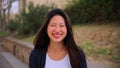 Close up individual portrait of chinese young woman smiling and looking at camera ourside. Front view of asian teenage