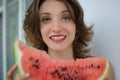 Close up indoors portrait of beautiful woman with short hair and sensual lips eating a piece of watermelon. Hedonism