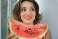 Close up indoors portrait of beautiful woman with short hair and sensual lips eating a piece of watermelon. Hedonism