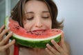 Close up indoors portrait of beautiful woman with short hair and sensual lips eating a piece of watermelon. Hedonism