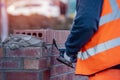 Close up of industrial bricklayer laying bricks on cement mix on construction site