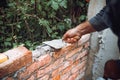 Close up of industrial worker, bricklayer installing bricks on exterior walls at construction site